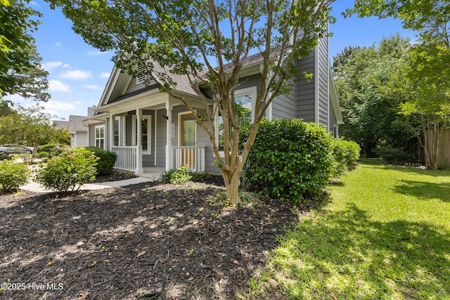 view of front facade with covered porch, a front lawn, and a chimney