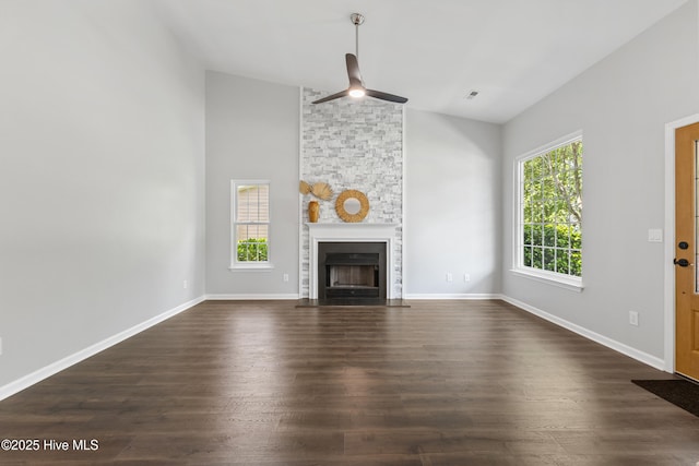unfurnished living room featuring vaulted ceiling, dark wood-style floors, a ceiling fan, a fireplace with flush hearth, and baseboards