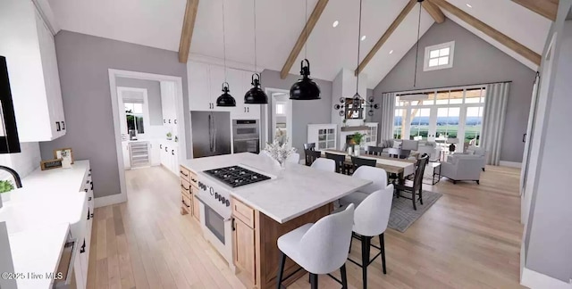 2112 Arnold Palmer Dr, Shallotte, NC 28470 - kitchen featuring stainless steel appliances, high vaulted ceiling, beamed ceiling, light wood-style floors, and a breakfast bar area
