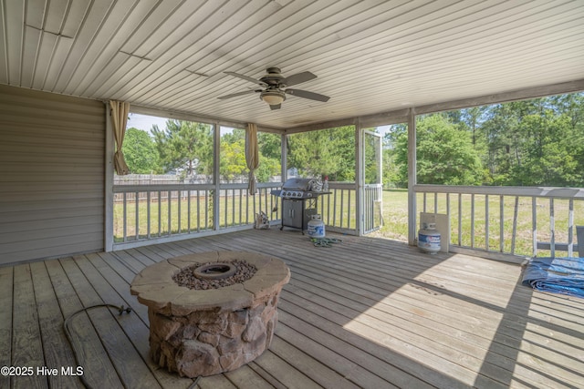 wooden deck with area for grilling, ceiling fan, a yard, and view of scattered trees