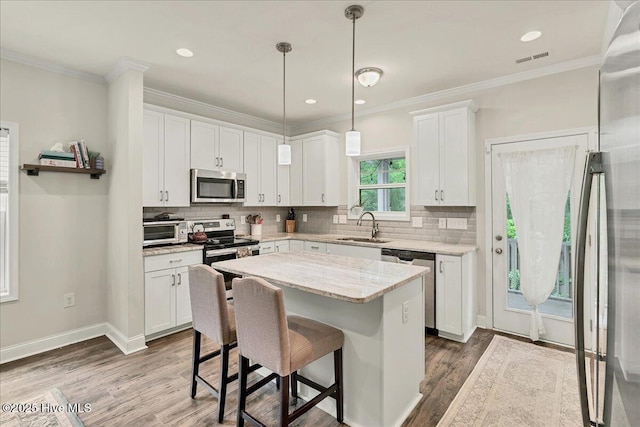 11 Bedford Cir, Pinehurst, NC 28374 - kitchen with appliances with stainless steel finishes, a sink, wood finished floors, white cabinets, and decorative backsplash