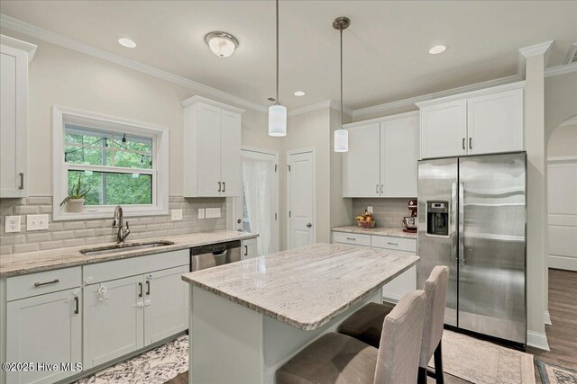 11 Bedford Cir, Pinehurst, NC 28374 - kitchen with appliances with stainless steel finishes, a sink, ornamental molding, white cabinetry, and a kitchen island