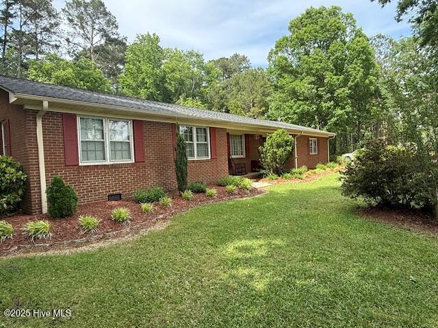 view of front of property with a front lawn, brick siding, and crawl space