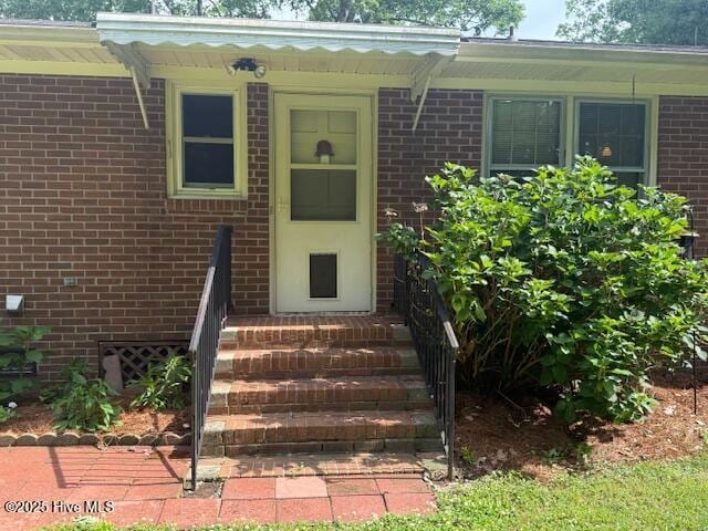 doorway to property featuring brick siding