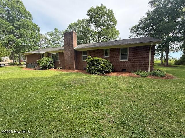 back of house with a chimney, a yard, brick siding, and crawl space