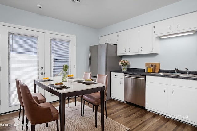 2414 Educational Dr, New Bern, NC 28562 - kitchen featuring stainless steel dishwasher, a sink, dark wood finished floors, dark countertops, and white cabinets