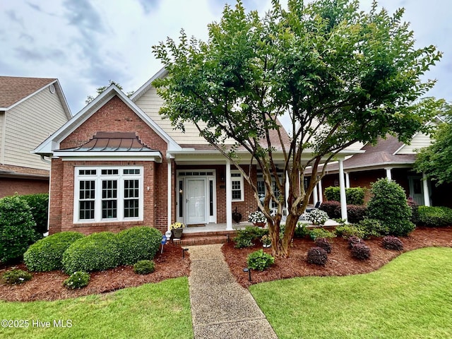 view of front of property with brick siding, a standing seam roof, a front yard, and metal roof