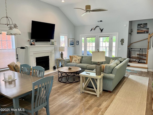 living area featuring light wood-style floors, lofted ceiling, ceiling fan, a premium fireplace, and stairs