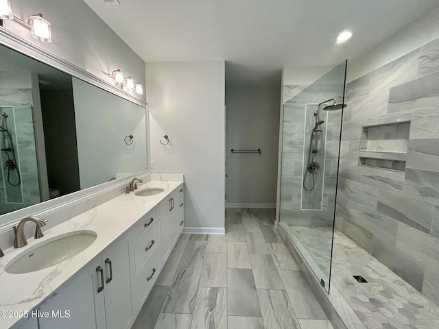 bathroom featuring a walk in shower, double vanity, and baseboards