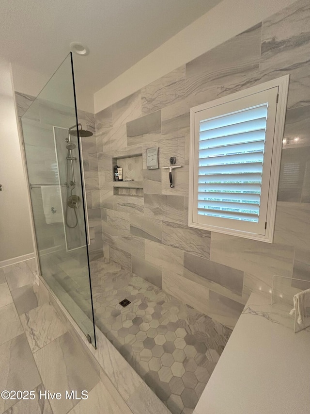 full bath featuring a tile shower and marble finish flooring