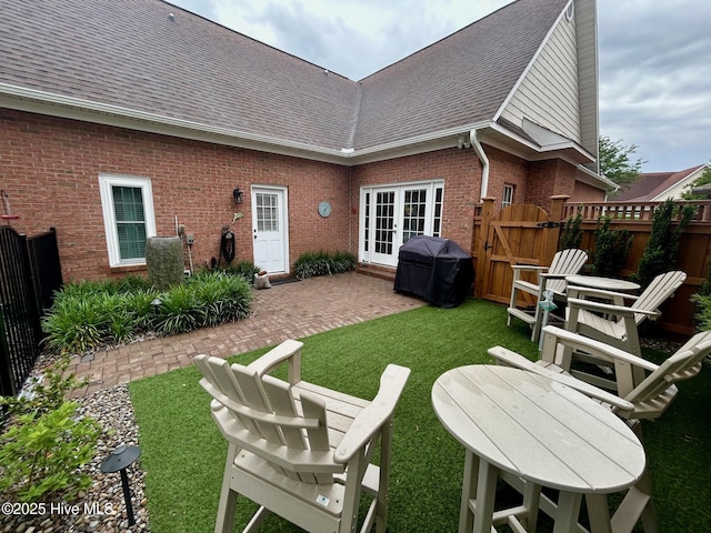 rear view of property featuring brick siding, french doors, a shingled roof, and a patio area