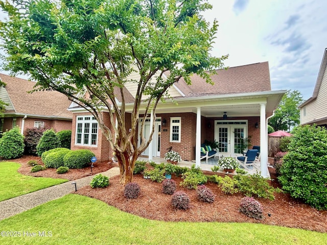 view of front facade featuring french doors, brick siding, a patio, and a shingled roof