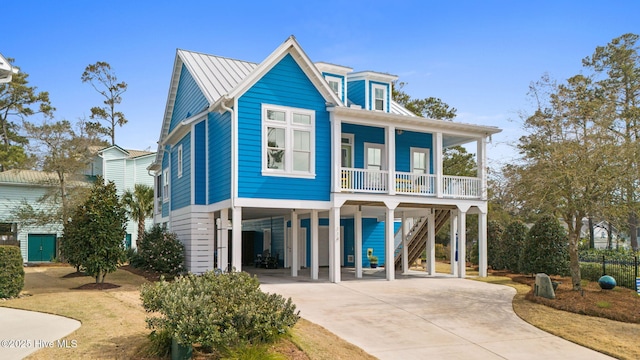 114 Lucas Cv, Oak Island, NC 28465 - view of front of home featuring a carport, covered porch, driveway, stairs, and metal roof
