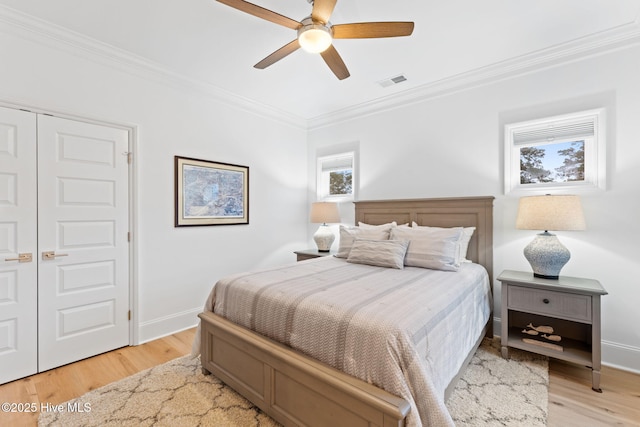 114 Lucas Cv, Oak Island, NC 28465 - bedroom featuring crown molding, light wood-style floors, baseboards, ceiling fan, and a closet