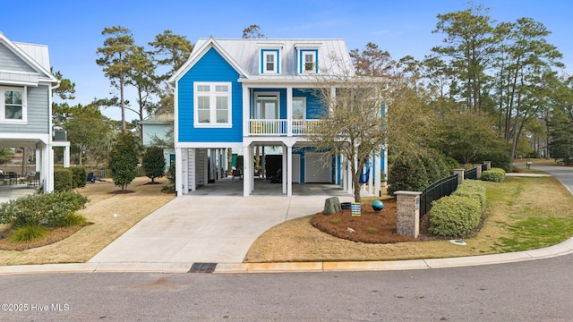 114 Lucas Cv, Oak Island, NC 28465 - coastal home featuring a carport, concrete driveway, metal roof, and covered porch