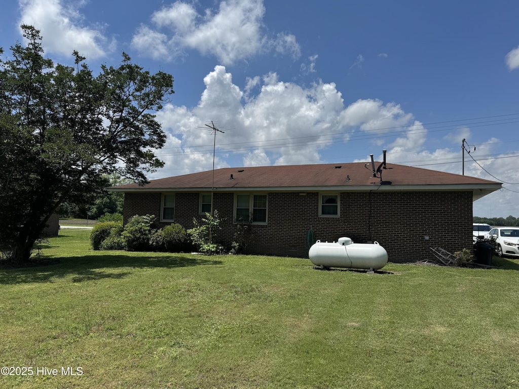 back of house with a lawn and brick siding