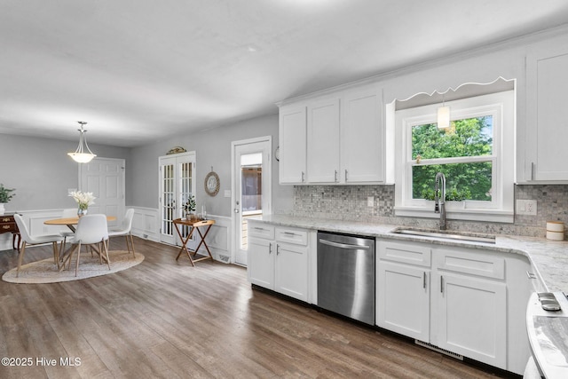 kitchen with dishwasher, a sink, decorative backsplash, white cabinets, and a wainscoted wall