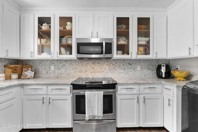 kitchen featuring stainless steel appliances, white cabinets, glass insert cabinets, decorative backsplash, and light stone countertops