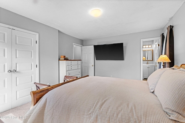 bedroom featuring carpet, a closet, ensuite bathroom, and a sink
