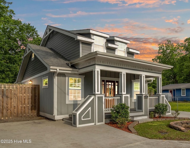 view of front of house with fence, covered porch, board and batten siding, and a shingled roof