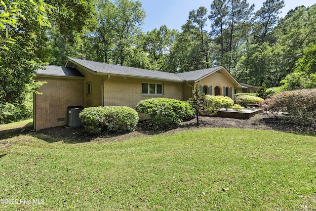 221 Quail Ridge Rd, Wilmington, NC 28409 - view of side of home featuring a lawn, brick siding, central AC unit, and view of scattered trees
