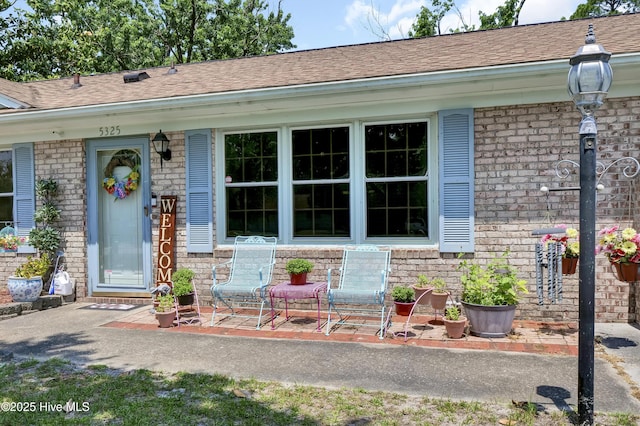 5325 Lord Tennyson Rd, Wilmington, NC 28405 - doorway to property featuring brick siding, a porch, and roof with shingles