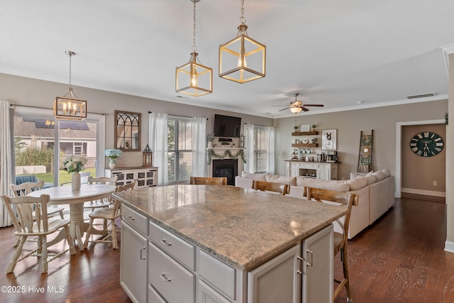 433 Landsdowne Cir, Hampstead, NC 28443 - kitchen featuring a glass covered fireplace, a center island, dark wood-style floors, crown molding, and ceiling fan