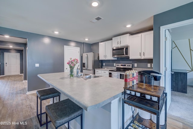 1145 Saint Augustine Dr, Castle Hayne, NC 28429 - kitchen featuring appliances with stainless steel finishes, a sink, white cabinetry, a breakfast bar, and recessed lighting