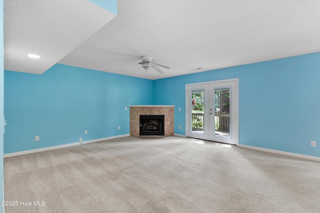 935 Birch Creek Dr, Wilmington, NC 28403 - unfurnished living room featuring ceiling fan, carpet flooring, a tiled fireplace, a textured ceiling, and french doors