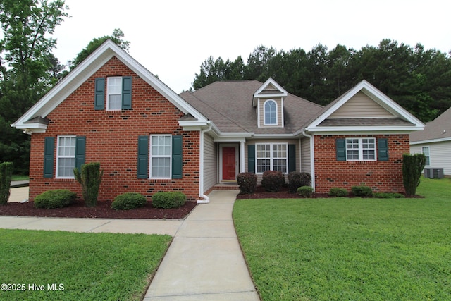traditional home with brick siding, cooling unit, a front lawn, and roof with shingles