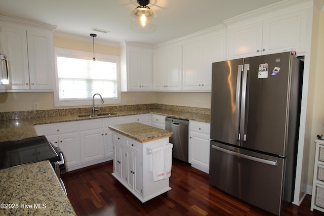 kitchen featuring appliances with stainless steel finishes, a sink, dark wood finished floors, white cabinets, and light stone countertops