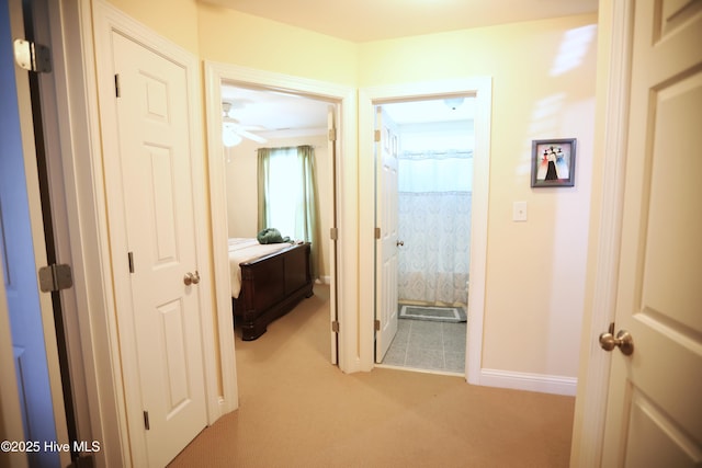 hall featuring light carpet and baseboards