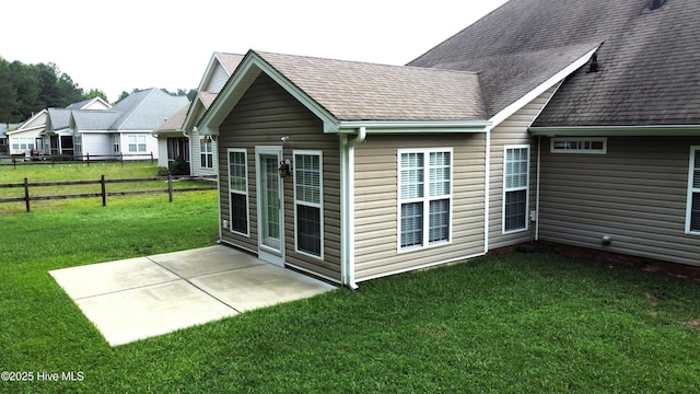 rear view of house featuring a patio and roof with shingles