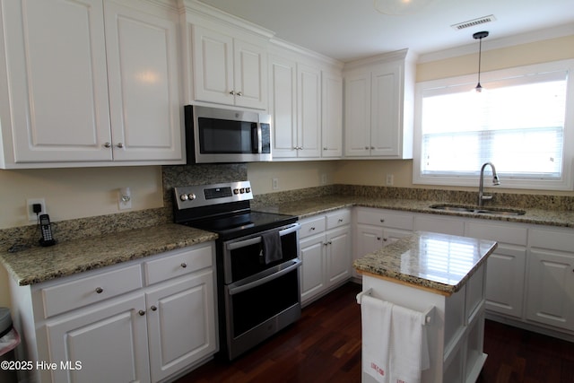 kitchen with stainless steel appliances, a sink, dark wood finished floors, white cabinetry, and ornamental molding