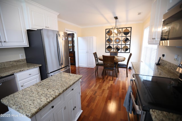 kitchen with appliances with stainless steel finishes, ornamental molding, white cabinets, dark wood-style flooring, and light stone counters