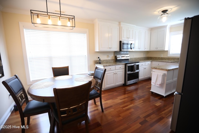 kitchen featuring stainless steel appliances, ornamental molding, white cabinetry, dark wood-style flooring, and hanging light fixtures