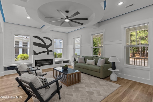 9213 Rivendell Pl SW, Calabash, NC 28467 - living room with a decorative wall, ceiling fan, light wood-style flooring, a glass covered fireplace, and plenty of natural light