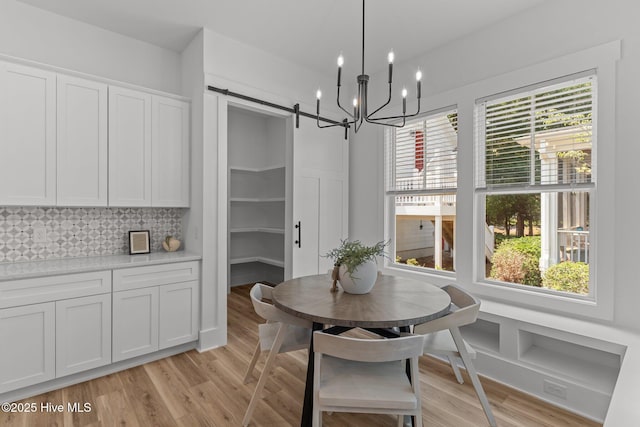 9213 Rivendell Pl SW, Calabash, NC 28467 - dining area with light wood-style floors, a barn door, and a chandelier