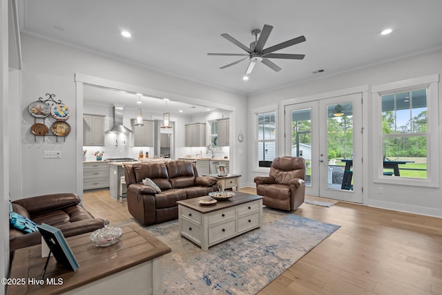 living area featuring a ceiling fan, crown molding, recessed lighting, light wood-style flooring, and baseboards