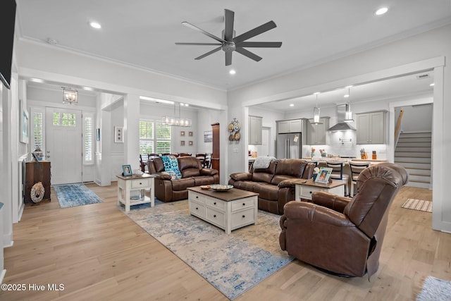 living room with crown molding, light wood-type flooring, ceiling fan, recessed lighting, and stairway