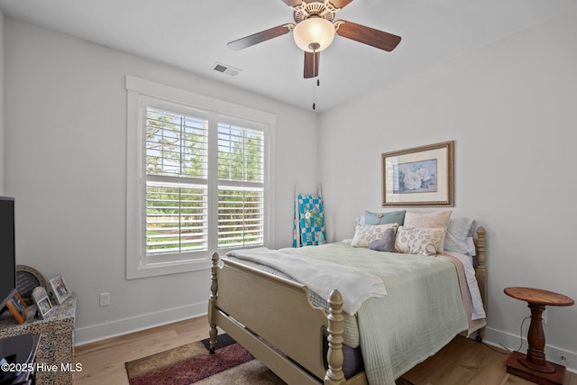 bedroom with multiple windows, wood finished floors, baseboards, and ceiling fan
