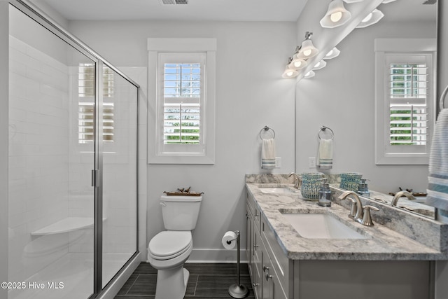 bathroom featuring toilet, healthy amount of natural light, a stall shower, and baseboards