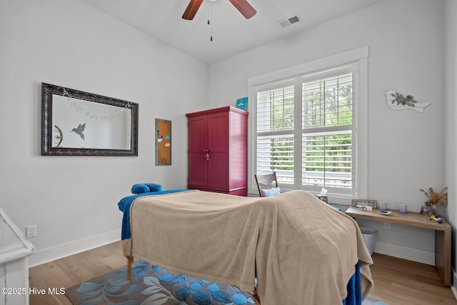 bedroom with wood finished floors, baseboards, and multiple windows