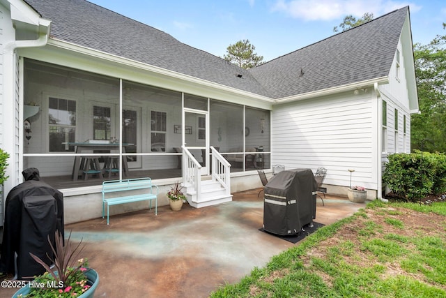 back of house featuring a sunroom, roof with shingles, and a patio area