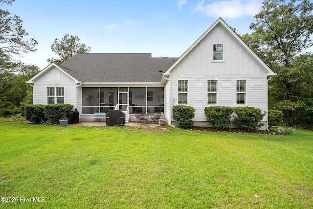 back of property with a sunroom, board and batten siding, a shingled roof, and a lawn