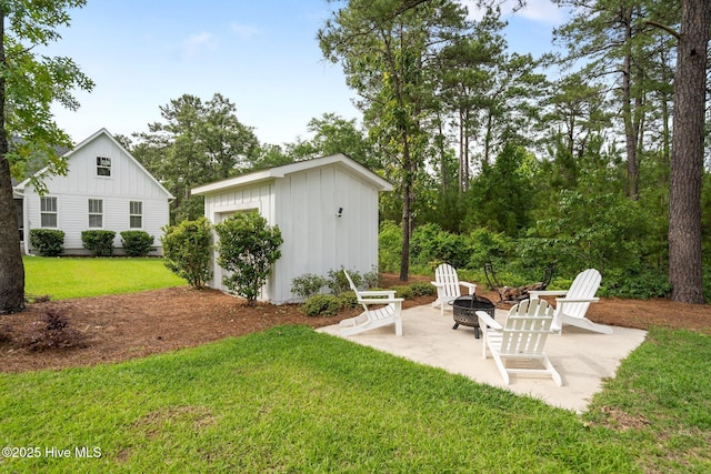 view of grassy yard with an outdoor fire pit, an outdoor structure, and a patio area