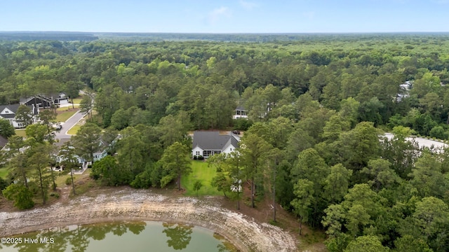 aerial view of property and surrounding area with a heavily wooded area and a large body of water
