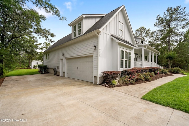 view of side of property with board and batten siding, a porch, concrete driveway, a yard, and a shingled roof