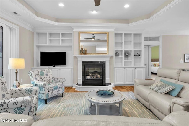 1013 Dowling Ct, Leland, NC 28451 - living area with a ceiling fan, light wood-type flooring, a glass covered fireplace, ornamental molding, and built in features