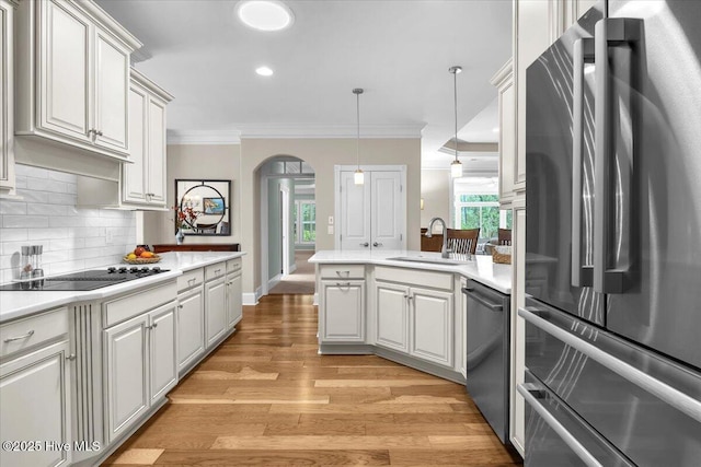 1013 Dowling Ct, Leland, NC 28451 - kitchen featuring stainless steel appliances, a sink, a peninsula, arched walkways, and tasteful backsplash
